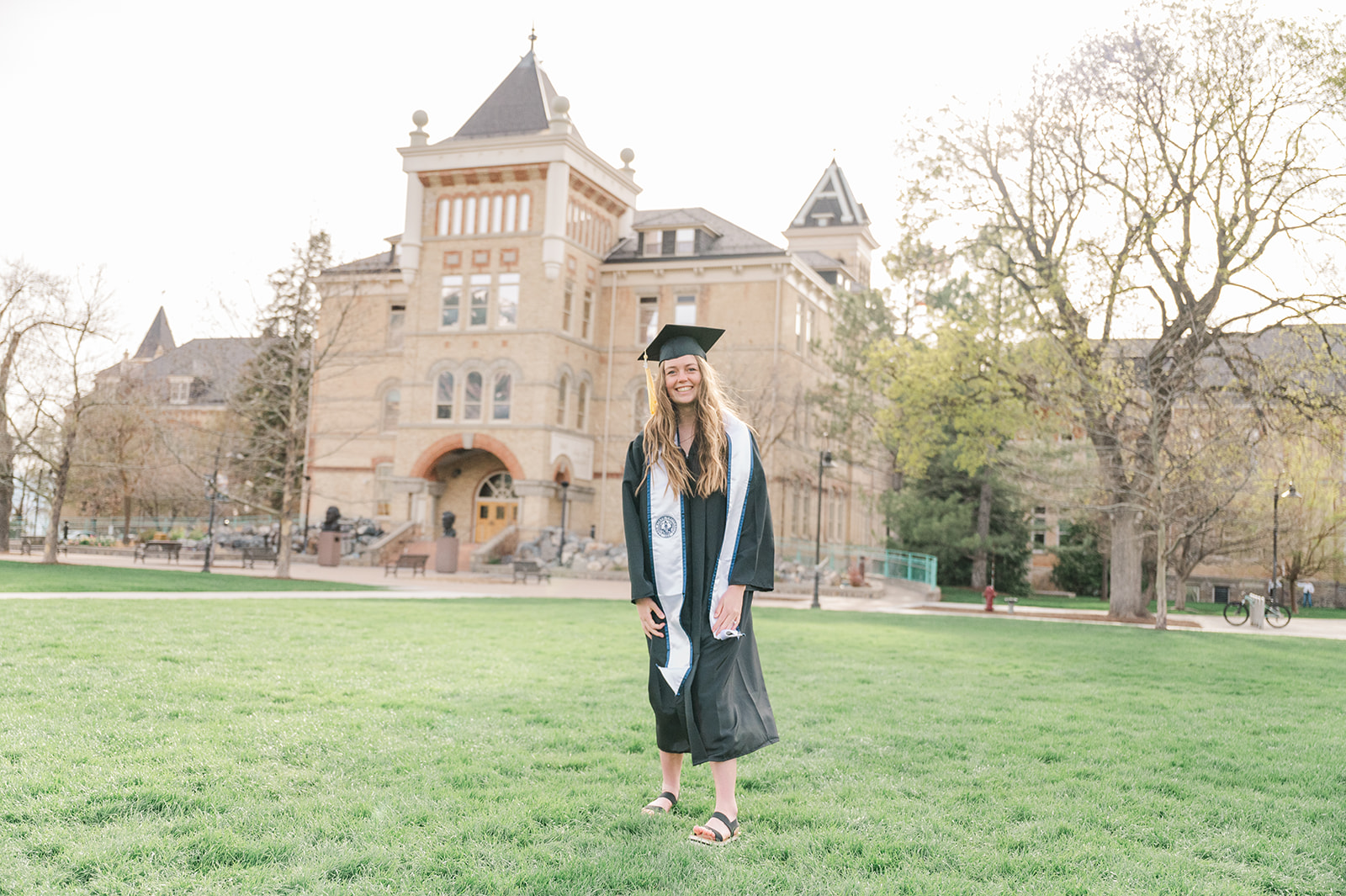 Anna standing in front of Old Main in graduation clothes